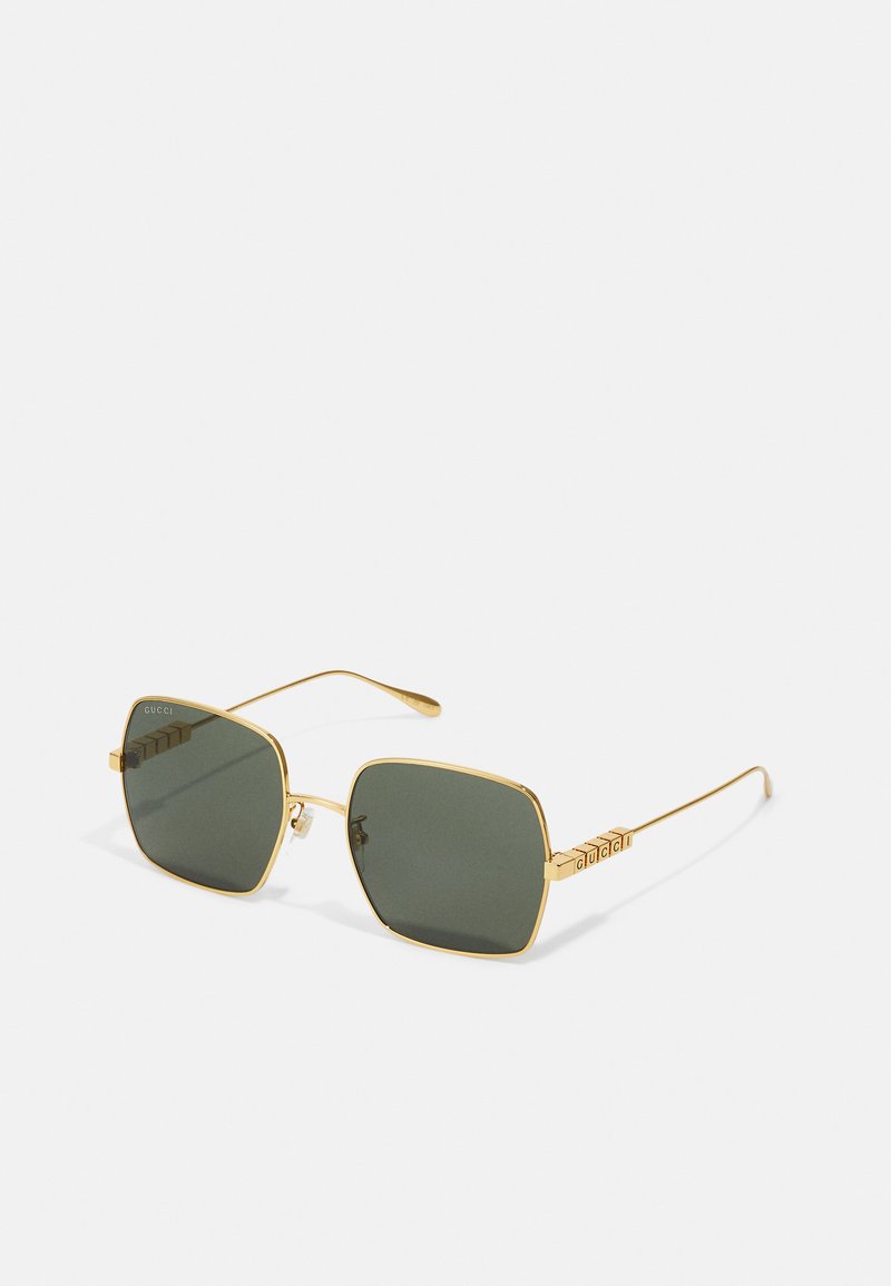 Gold metal sunglasses with square lenses, green shades, and a textured side detailing featuring the brand name in 3D letters.