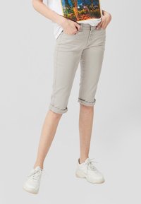 Pantalones gris claro hasta la rodilla con un ajuste slim, frente de cinco botones y puños enrollados. Combinados con una camiseta blanca y zapatillas blancas.