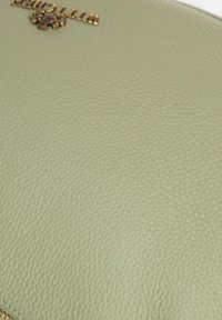Copertura per notebook in pelle verde texturizzata con logo dorato impresso. Presenta una superficie liscia e un sottile motivo a grana.
