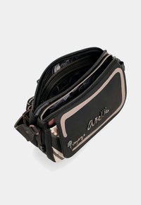 Borsa a tracolla in pelle nera con più scomparti con zip, dettagli beige e una fodera interna a motivo. Presenta un logo sul davanti.
