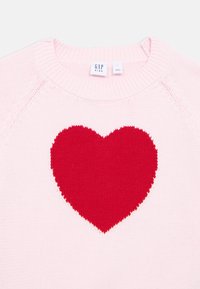 Light pink knitted sweater with a large red heart design on the front. Features a round neckline and ribbed cuffs. Brand label visible.