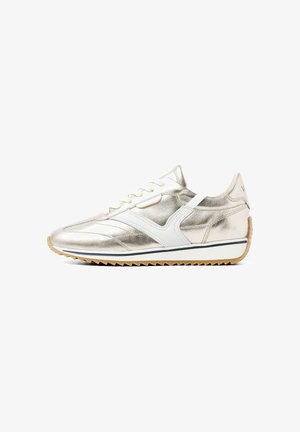 Metallisch goldene Sneaker mit weißen Akzenten, Schnürdesign, gepolsterter Zunge und gerippter Gummisohle. Verfügt über gestickte Details und Logo an der Ferse.