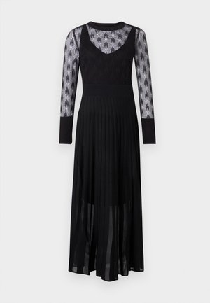 Vestido negro con un top transparente y con estampado de mangas largas, escote ancho y una falda plisada que llega hasta el suelo.