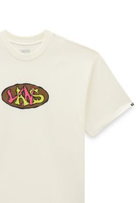 Cremefarvet t-shirt med et grafisk logo i pink og grøn på en brun oval baggrund. Korte ærmer og rund halsudskæring.