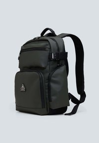 Zielony oliwkowy plecak wykonany z trwałego materiału. Posiada wiele zamykanych na zamek kieszeni, wyściełane ramiączka i górny uchwyt. Akcentowany czarnymi z zamkami.