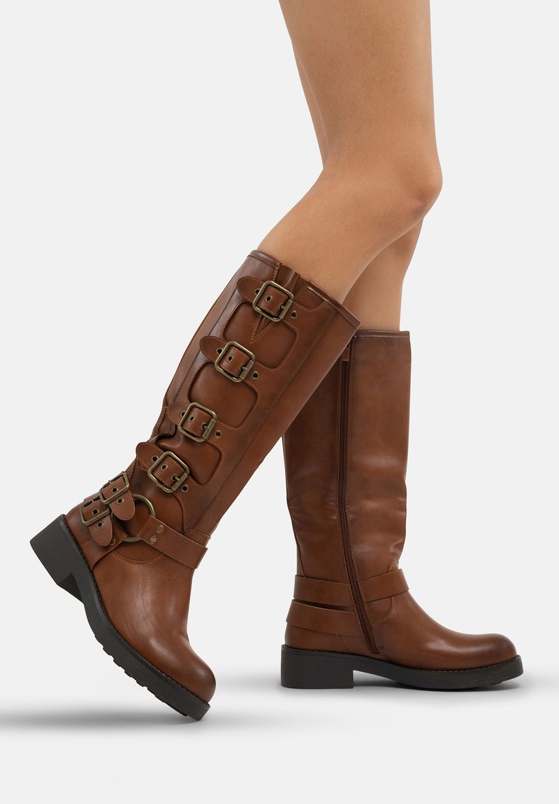 Botas de cuero marrón hasta la rodilla con múltiples detalles de hebilla, puntera redondeada, paneles laterales texturizados y un tacón bajo y grueso.