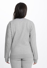 Felpa grigia con maniche lunghe, polsini e orlo a coste. Tessuto morbido e testurizzato con scollatura a girocollo, che mostra un design semplice e classico.
