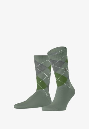 Groene en grijze argyle sokken van zacht materiaal, met gestructureerde ribbels en witte details langs het ruitpatroon.