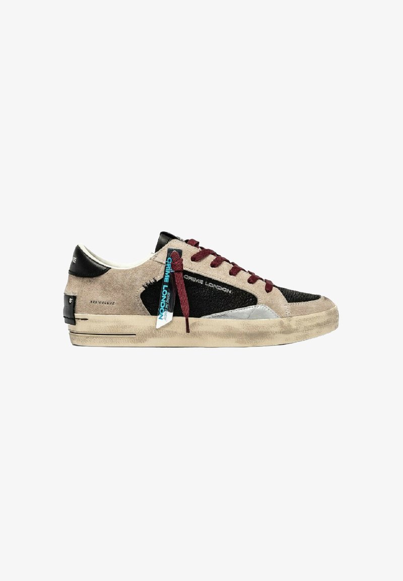 Zapatilla de corte bajo con ante beige, paneles texturizados en negro, cordones burdeos, etiqueta azul "Crime London" y una suela beige desgastada.