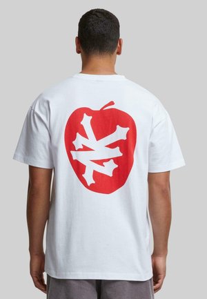 White cotton t-shirt featuring a large red apple graphic with a white bone pattern on the back. Short sleeves and a relaxed fit.