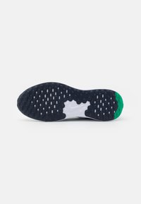 Semelle de chaussure de course Nike, présentant un design noir et blanc avec des motifs de traction multidirectionnels. Accent vert au niveau du talon.