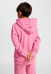 Rosa Kapuzenpullover aus weichem Material mit legerer Passform. Verfügt über eine Kapuze mit Kordelzug und gerippte Bündchen. Wird mit passenden Hosen getragen.