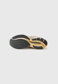 Sport shoe outsole featuring a textured black rubber surface with a beige midsole and subtle green accent. Sole design enhances traction.