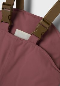 Tissu texturé couleur mauve avec des bretelles réglables brunes et une boucle en plastique. Le bord de la poche est visible, avec une doublure blanche uni à l'intérieur.
