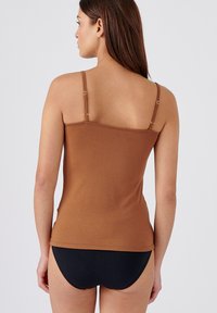 Brown sleeveless top with adjustable straps, form-fitting design, made of smooth fabric, paired with black briefs.