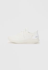 Chaussure de sport blanche avec une tige en tricot texturé, un laçage à l'avant et une semelle en caoutchouc blanc épaisse et rainurée. Détails minimaux et finition lisse.