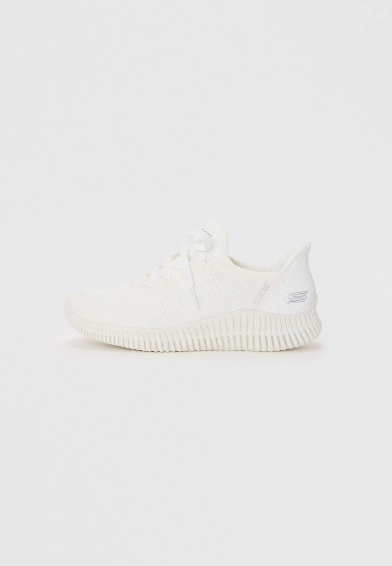 Chaussure de sport blanche avec une tige en tricot texturé, un laçage à l'avant et une semelle en caoutchouc blanc épaisse et rainurée. Détails minimaux et finition lisse.