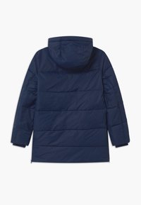 Námořnická modrá zateplená zimní bunda s kapucí, dlouhými rukávy a vodorovným prošíváním, zobrazená ze zadní strany na bílém pozadí.