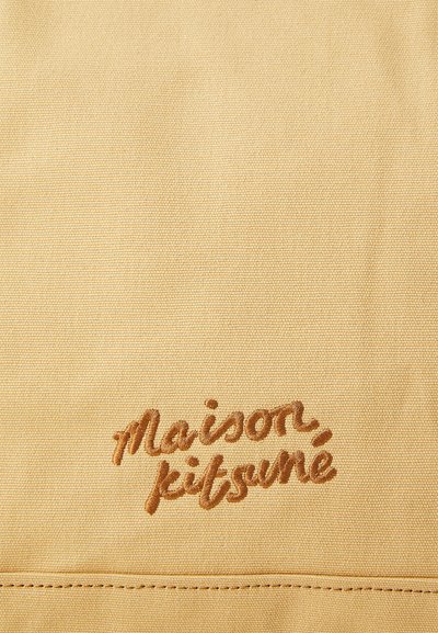 Pješački materijal s teksturiranim tkanjem, s smešnim izvezenim natpisom "maison kitsuné." Jednostavan dizajn bez dodatnih detalja ili hardvera.