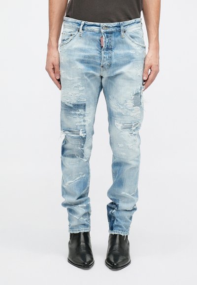 Jeans en denim bleu clair avec effet usé, coupe slim. Présentent des déchirures et des bords effilochés, cinq poches et une fermeture à bouton standard.