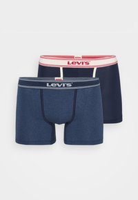 Dve sady pánskych boxeriek Levi's. Jedny sú tmavo námorníckej farby s kontrastným červeným a bielym pásom, zatiaľ čo druhé sú melírované námorníckej modrej.