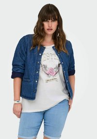 Giacca in denim trapuntato con bottoni a pressione sopra una t-shirt grafica con design di rosa e ali, abbinata a pantaloncini in denim blu chiaro.