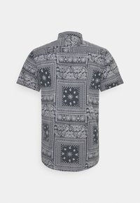 Camisa de manga corta con un estampado de paisley en blanco y negro, cuello abotonado y tejido texturizado con un diseño detallado.