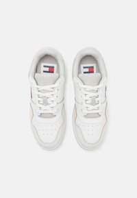 Bílé kožené tenisky s síťovinovými detaily, se šněrovacím designem, perforovanou špičkou a bočními panely a s logem v červené, bílé a modré barvě.