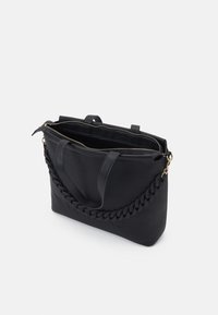 Černá kožená taška přes rameno s pleteným popruhem, horním zipovým uzávěrem a raženým logem. Má dvojité uchy a prostorný interiér.