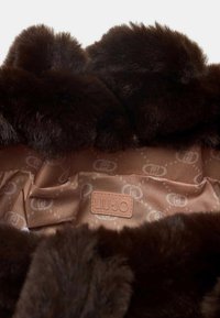 Interno in finta pelliccia marrone con una morbida fodera in satin, caratterizzata da un motivo a emblemi discreti e un'etichetta in pelle con il logo "LIU·JO."