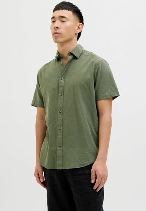 Camicia a maniche corte, con bottoni, di colore verde oliva, realizzata in tessuto testurizzato con colletto e bottoni frontali. Presenta una vestibilità rilassata.