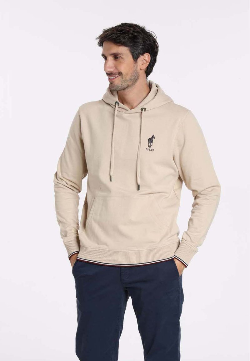Hoodie beige en coton, avec une poche kangourou, des cordons de serrage et un petit logo sur la poitrine. Poignets et ourlet côtelés, texture lisse.