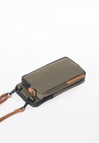 Olive green fabric wallet with black zipper, tan leather accent, and detachable strap. Rectangular shape with smooth texture and minimal detailing.