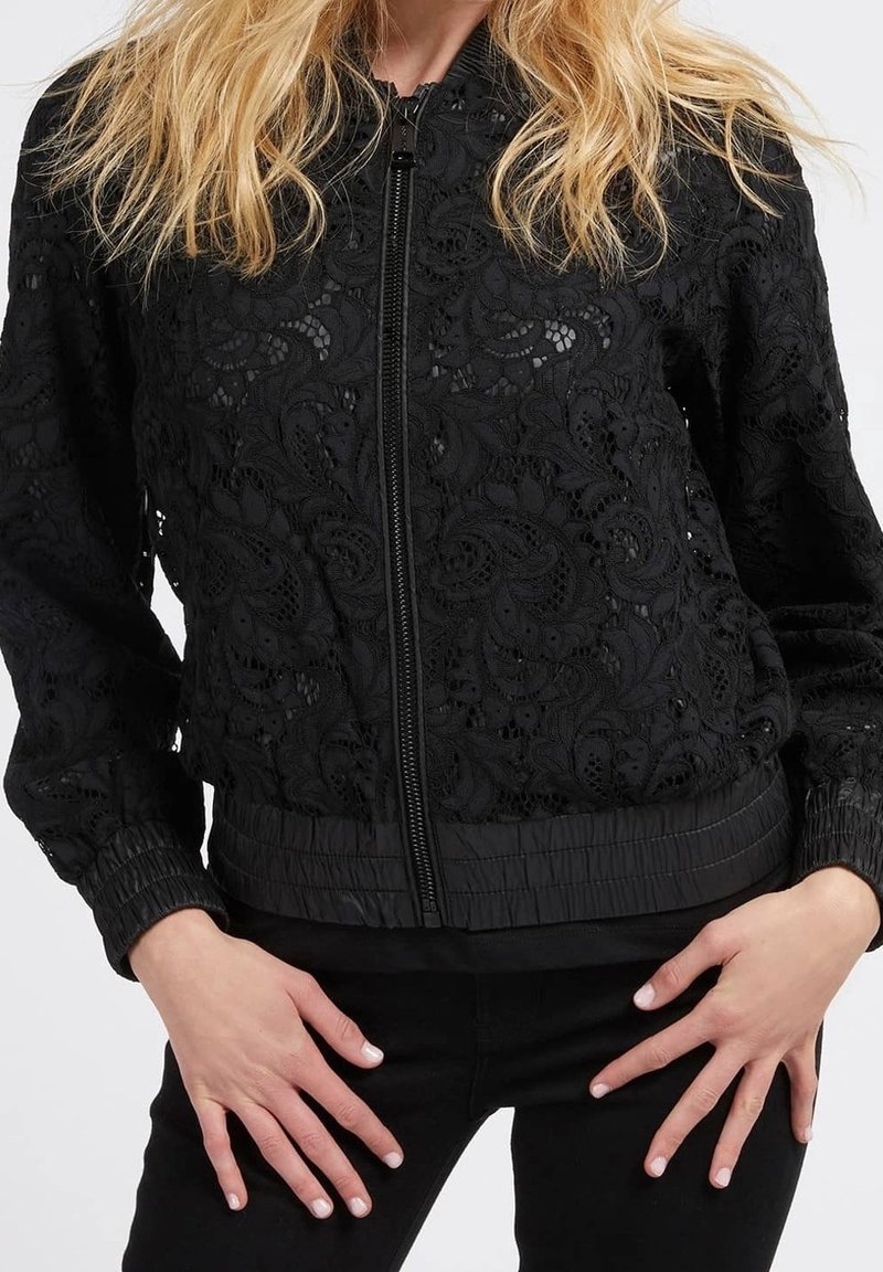 Black bomber jacket featuring a floral lace overlay, ribbed cuffs and hem, zip closure, and a textured, lightweight fabric.