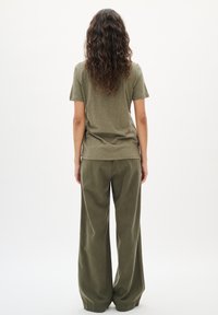 Olijfgroen, kortermig T-shirt uit het zachte, gestructureerde materiaal, gecombineerd met een wijde broek. De outfit heeft een ontspannen pasvorm.