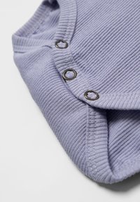 Lavender ribbed fabric garment with three metal snap buttons along the front. Features a soft, textured finish and folded edges.