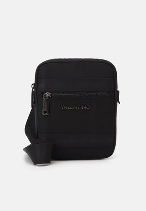 Musta neliönmuotoinen olkalaukku, jossa etutasku vetoketjulla, leveä säädettävä olkahihna ja "VALENTINO"-logo metallikirjaimin edessä.