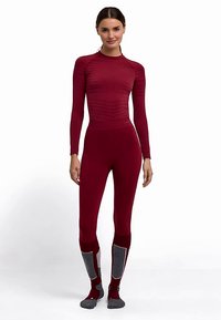 Bordeauxkleurige thermische top en legging set met geribbelde textuur, lange mouwen, aangesloten ontwerp en contrasterende grijze accenten op de benen en sokken.