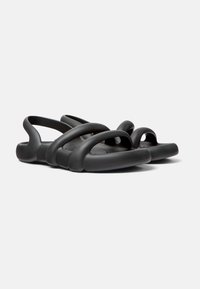 Musta sandaalit, jotka on valmistettu joustavasta materiaalista, ja joissa on useita vaakasuoria hihnoja sekä pyöreä varvassuunnittelu. Liukas pinta ja ergonominen muoto.
