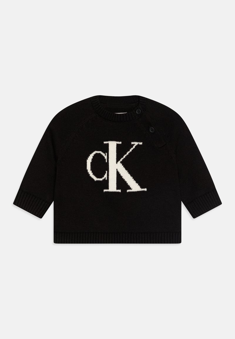 Maglione nero a maglia con maniche lunghe, caratterizzato da un grande logo bianco "CK" sulla parte anteriore e un colletto e orlo a coste. Due bottoni sulla spalla.
