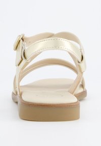 Gull metallisk sandal med flere stropper og en spenne. Har en polstret innersåle og en beige gummiksole. Bakre utsikt viser detaljene på stroppene.