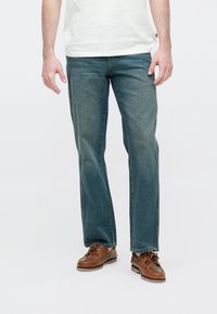 Τζιν παντελόνι σε ανοιχτό μπλε πλύσιμο, σχεδιασμός με ίσια γραμμή, στυλ με πέντε τσέπες, συνδυασμένο με καφέ δερμάτινα μποτάκια. Καθημερινό, χαλαρή εφαρμογή.