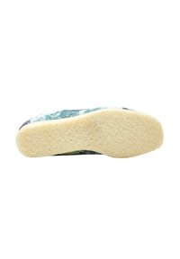 Suela de zapato con una base de goma texturizada, de color amarillento y con un patrón floral verde en la parte superior, con un diseño redondeado.