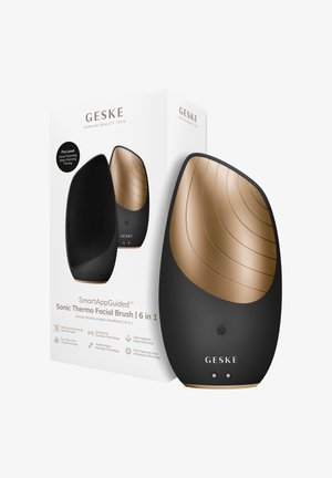 Strakke zwarte en gouden sonische thermo gezichtsborstel met getextureerde haren, naast witte verpakking met details over 6-in-1 huidverzorgingsfuncties.