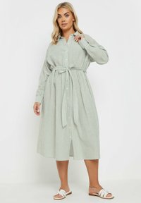 Randig skjortklänning i ljusgrön, med ett knytbälte, långa ärmar och en avslappnad passform. Tillverkad av ett lättviktigt material.