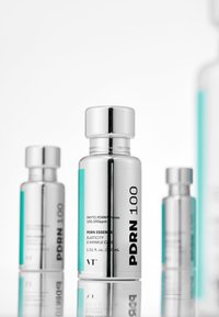 Silverfärgade glasflaskor med en elegant design, utrustade med ett metallock och en turkos etikett som visar "PDRN 100" och produktinformation.