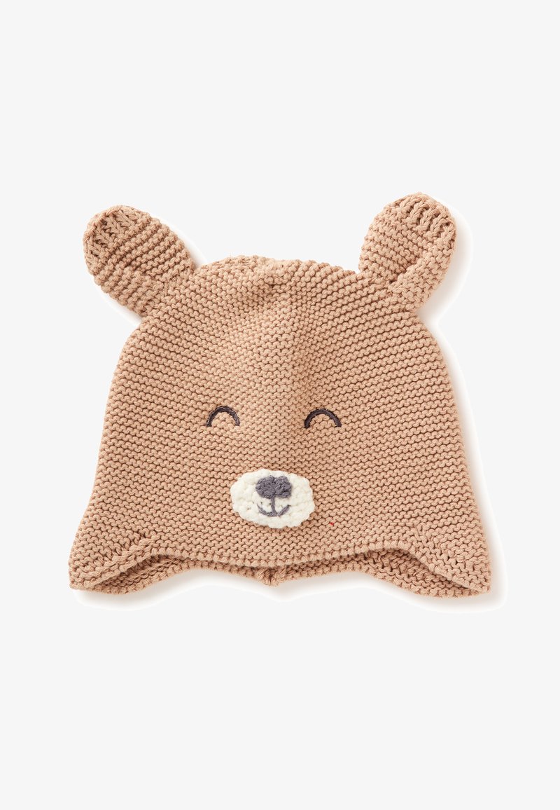 Bonnet de bébé beige tricoté avec des oreilles d'ours, des yeux souriants brodés et un museau blanc avec un nez gris sur fond blanc.