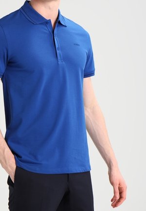 Niebieska koszulka polo z gładkiego materiału, z klasycznym kołnierzykiem, dwiema guzikami i subtelnym logo marki na piersi. Krótkie rękawy, luźny krój.