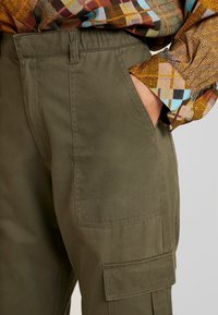 Gröna bomullscargobyxor med sidofickor och rak passform. Texturen är mjuk, med förstärkta sömmar och en klassisk midja.