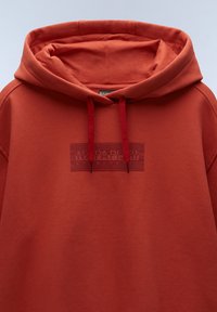 Rode hoodie met een kangoeroe-zak, textuur logo patch en trekkoorden. Gemaakt van zachte stof, met een ontspannen pasvorm.